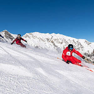 Zwei Skifahrer mit Skilehrer auf Skipiste
